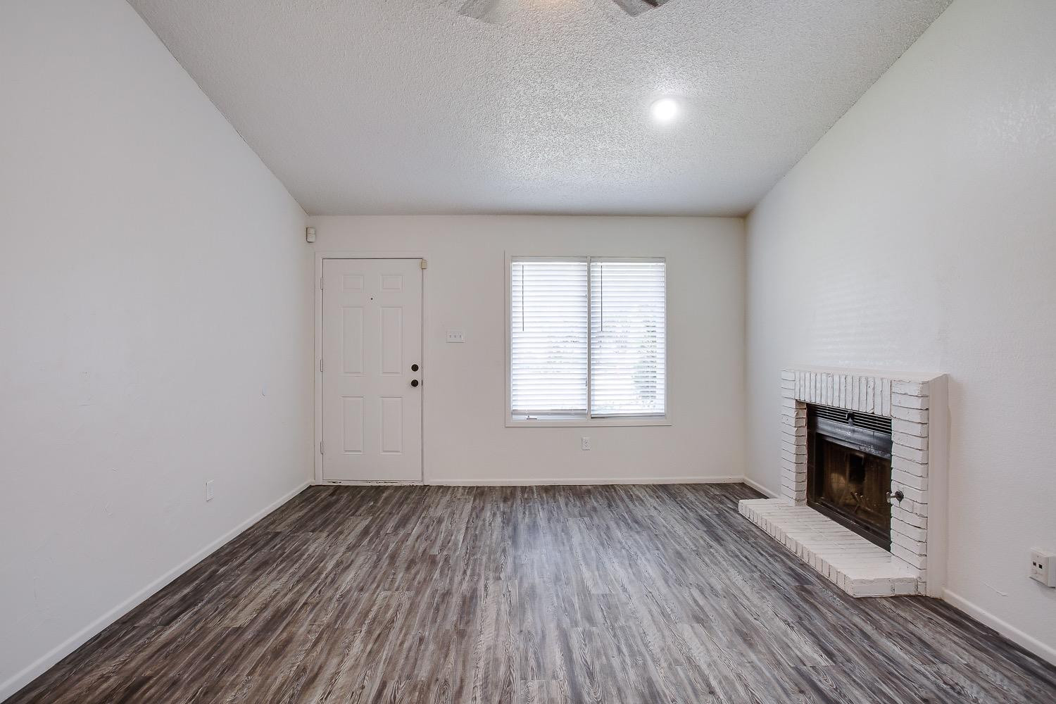 4749 2nd Street Lubbock, TX 79416 - Photo 9 of 13 an empty room with wooden floor a fireplace and windows