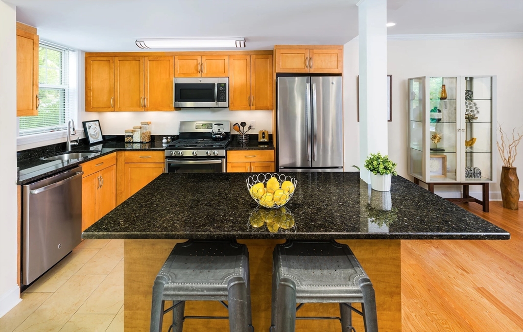 97 Gerry Road, Unit 97 Brookline, MA 02467 - Photo 3 of 6 a kitchen with stainless steel appliances granite countertop a stove a sink and a granite counter tops with a large window