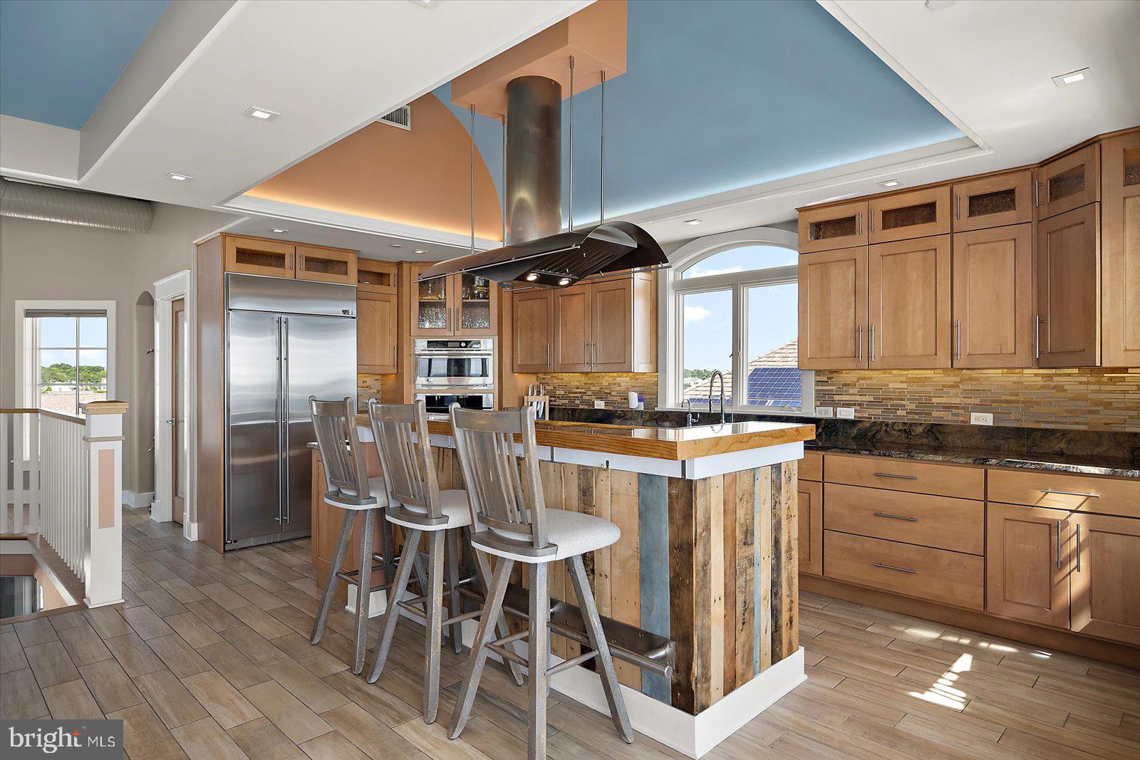 12957 Harbor Road Ocean City, MD 21842 - Photo 50 of 148 a kitchen with stainless steel appliances kitchen island granite countertop a table chairs cabinets and wooden floor