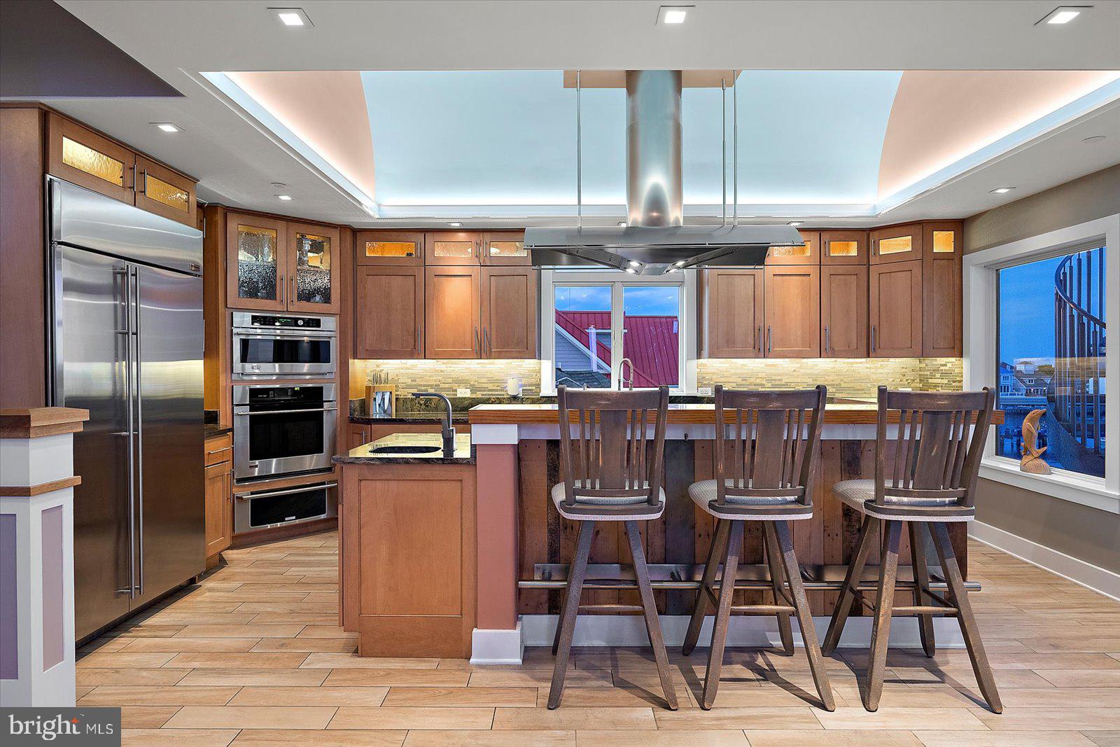 12957 Harbor Road Ocean City, MD 21842 - Photo 55 of 148 a kitchen with stainless steel appliances kitchen island granite countertop a dining table chairs sink and cabinets