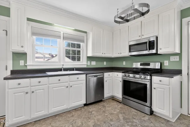 a kitchen with granite countertop white cabinets stainless steel appliances and a sink