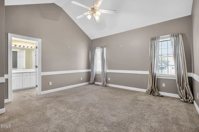 an empty room with chandelier fan and windows
