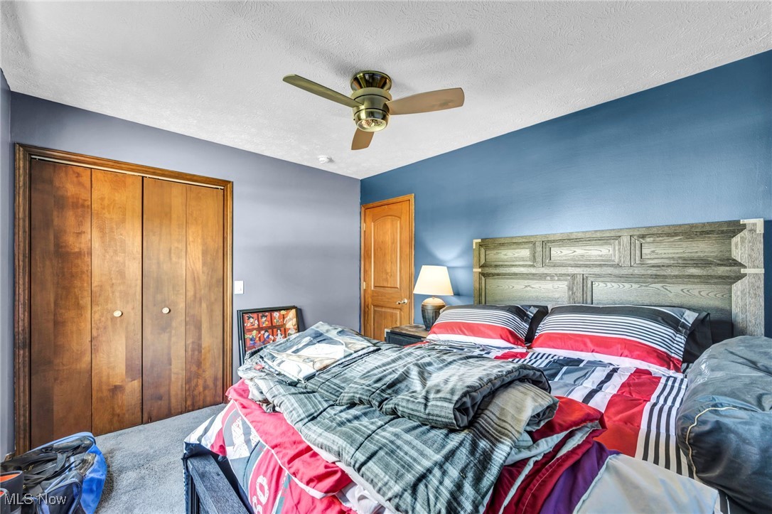 5704 McCartney Road Sandusky, OH 44870 - Photo 32 of 50 Carpeted bedroom featuring a textured ceiling, a closet, and a ceiling fan