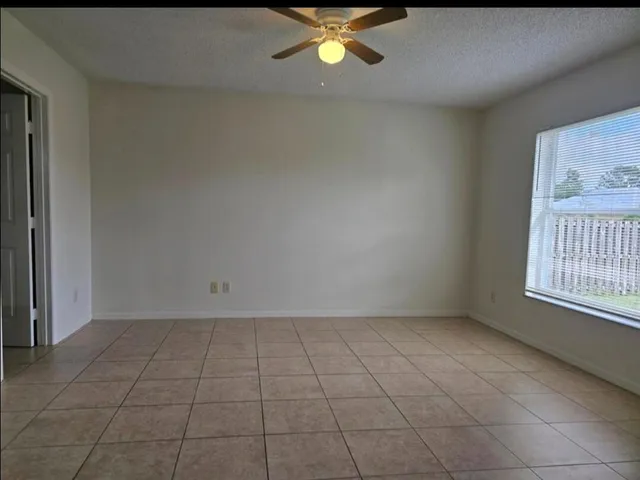 a view of an empty room with chandelier fan and fire place