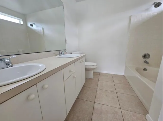a spacious bathroom with a granite countertop sink a toilet and bathtub