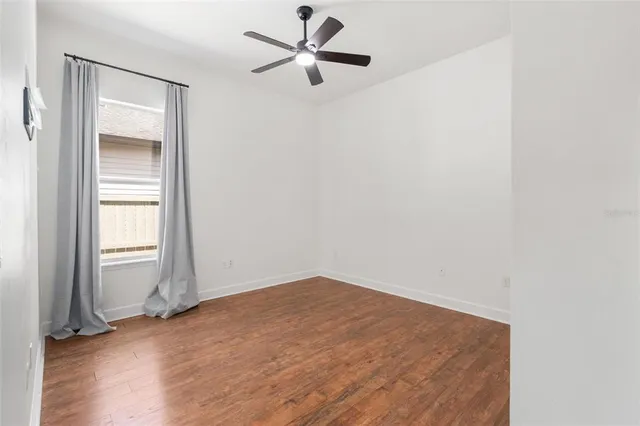 an empty room with a window and a ceiling fan