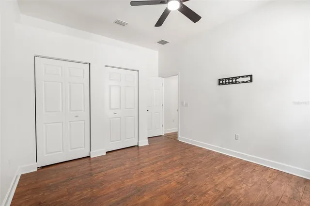 an empty room with ceiling fan and window