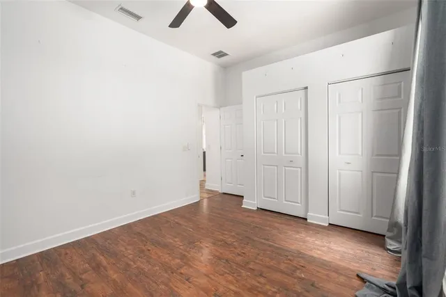 an empty room with ceiling fan and window