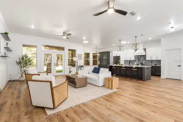 a living room with furniture kitchen view and a wooden floor