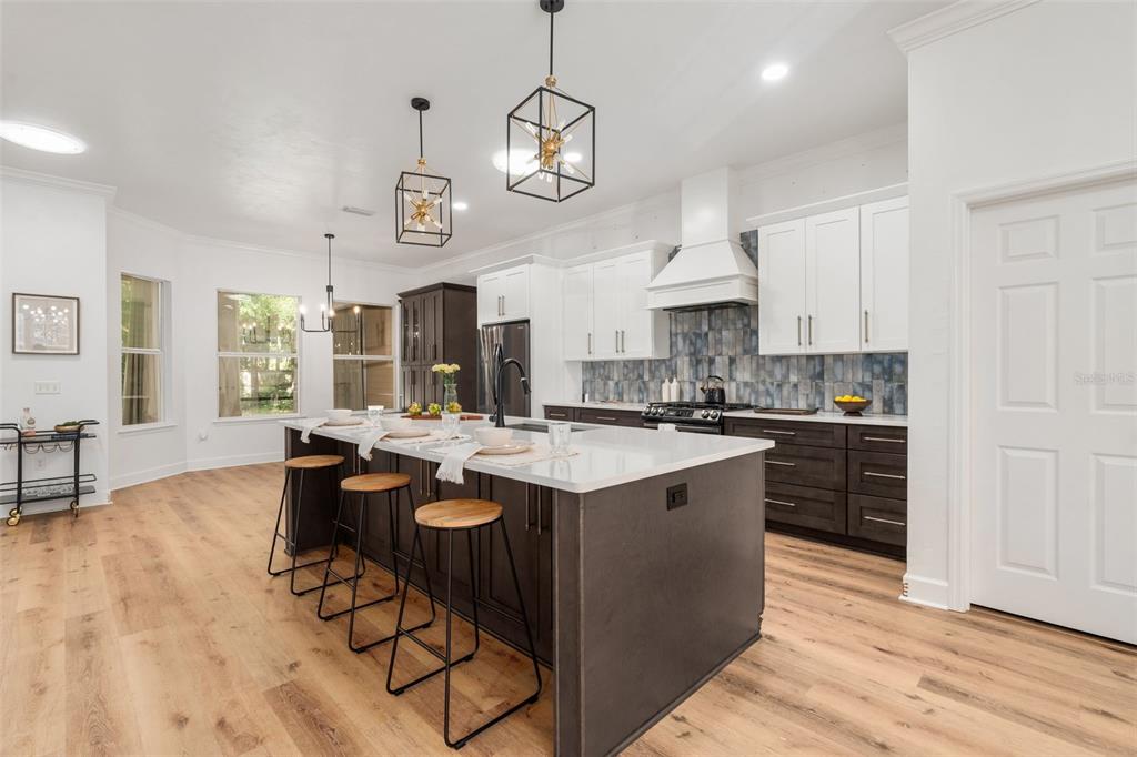6326 Southwest 90th Street Gainesville, FL 32608 - Photo 10 of 44 a kitchen with stainless steel appliances granite countertop a stove a sink dishwasher a dining table and chairs with wooden floor