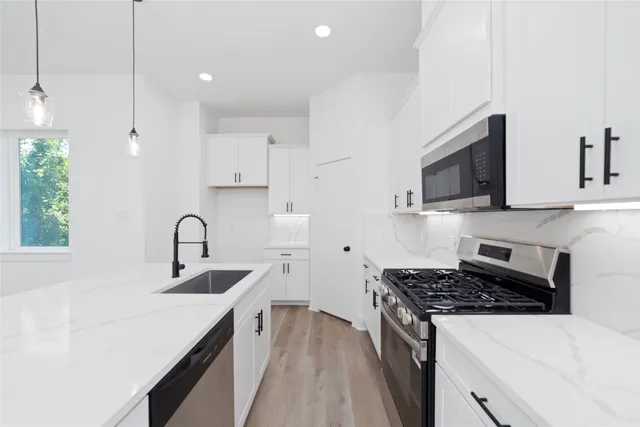 a kitchen with stainless steel appliances a sink stove and cabinets