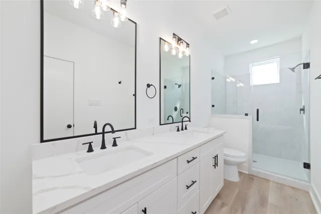 a bathroom with a double vanity sink toilet mirror and shower