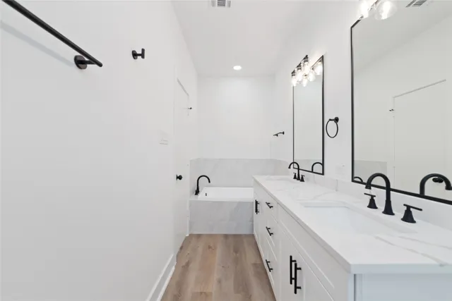 a spacious bathroom with a double vanity sink a mirror and a bathtub