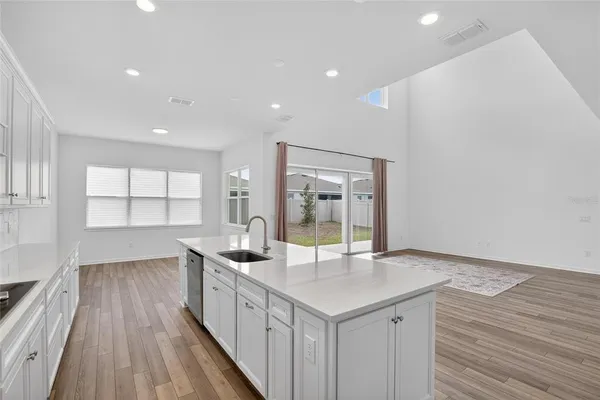 a kitchen with stainless steel appliances kitchen island granite countertop a stove a sink and white cabinets with wooden floor