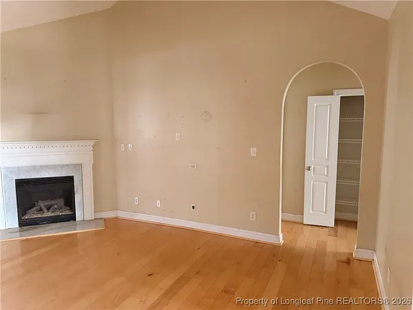 a view of empty room with wooden floor and fireplace