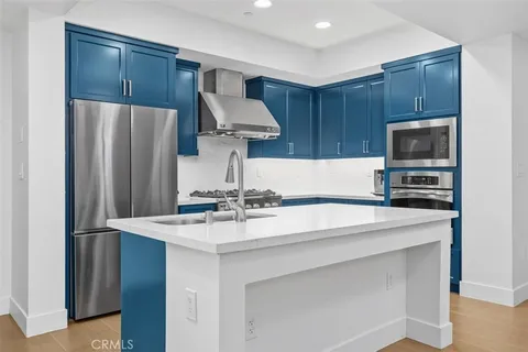 a hallway with cabinets a sink and wooden floor