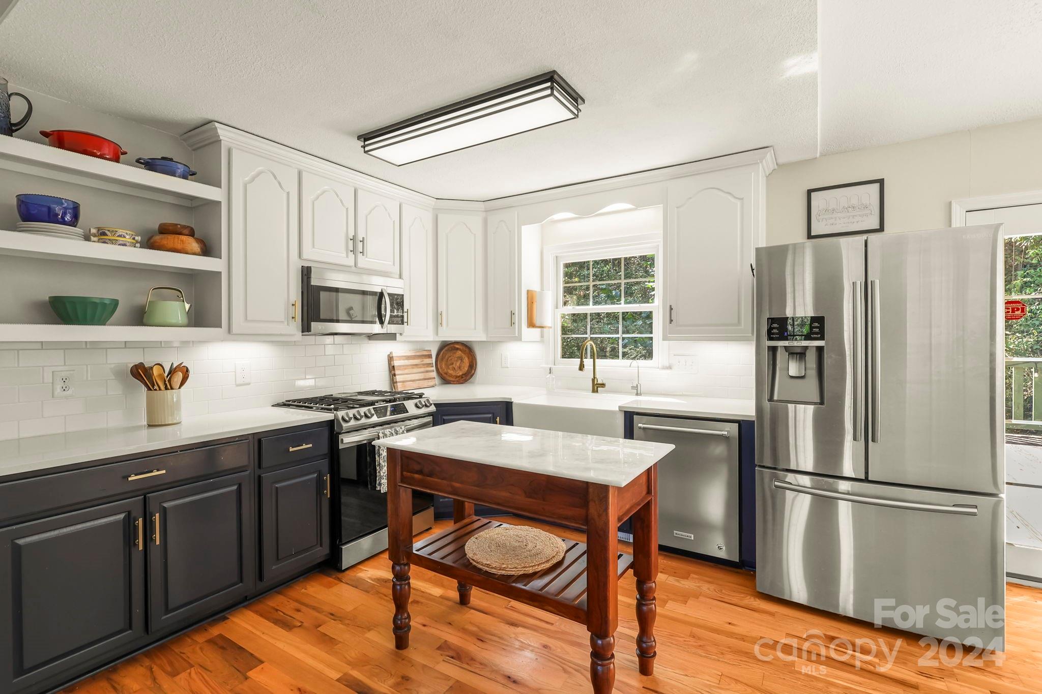 3409 Collettsville Road Lenoir, NC 28645 - Photo 10 of 48 a kitchen with stainless steel appliances granite countertop a refrigerator a sink dishwasher a stove and white countertops with wooden floor