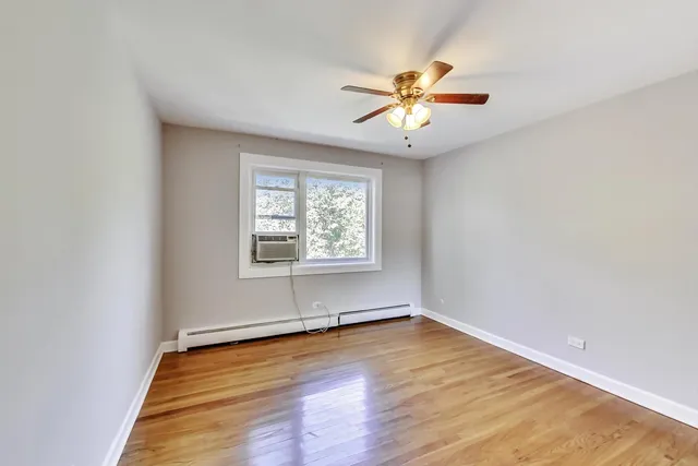 an empty room with wooden floor fan and windows