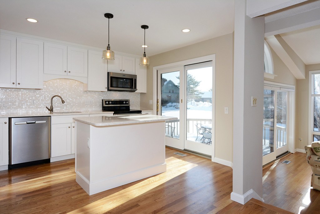 a kitchen with stainless steel appliances granite countertop a refrigerator a stove a sink and white cabinets with wooden floor