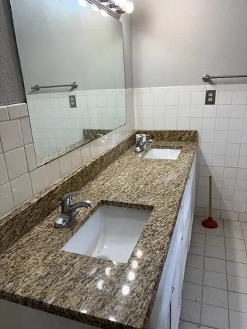 a bathroom with a granite countertop sink and a mirror