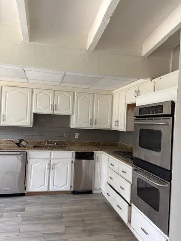 a kitchen with stainless steel appliances granite countertop a stove a sink and white cabinets