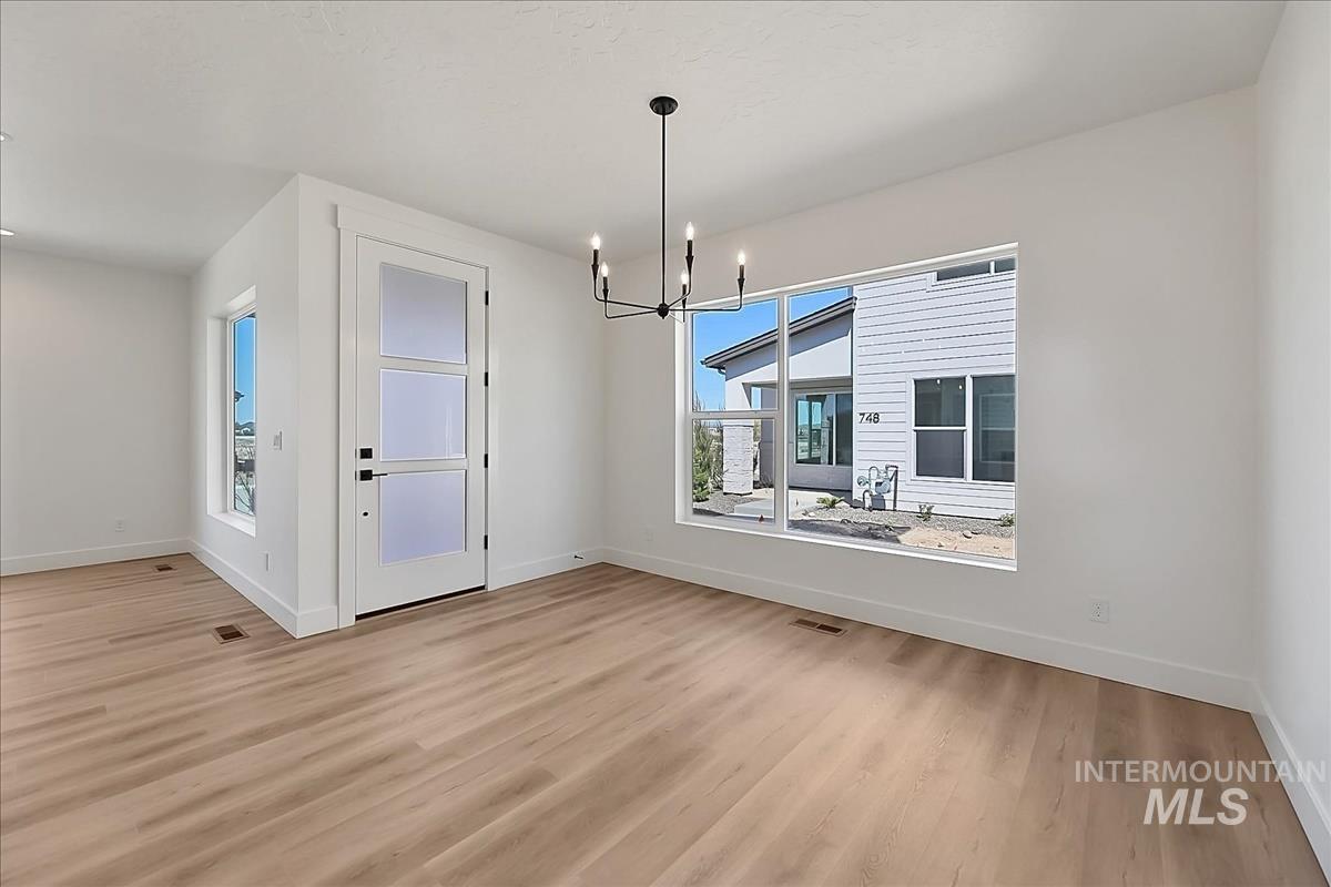 776 South Calhoun Lane Star, ID 83669 - Photo 16 of 49 Spacious room featuring light wood-finish flooring, white walls, and a modern black chandelier