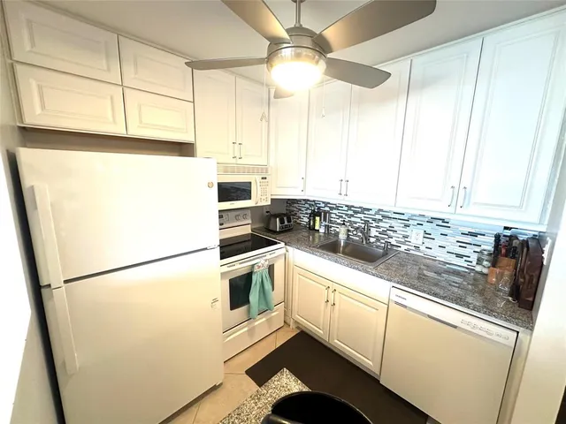 a kitchen with granite countertop white cabinets and white appliances