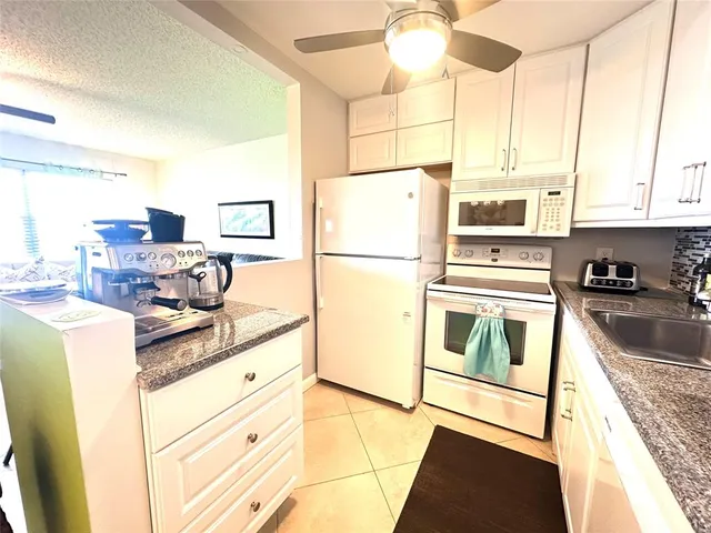 a kitchen with granite countertop a refrigerator a stove a sink and dishwasher with wooden floor