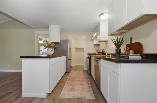 a kitchen with kitchen island granite countertop a sink and white cabinets