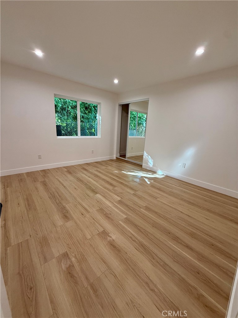 20407 Strathern Street, Unit 20409 Winnetka, CA 91306 - Photo 7 of 8 a view of an empty room with wooden floor and a window