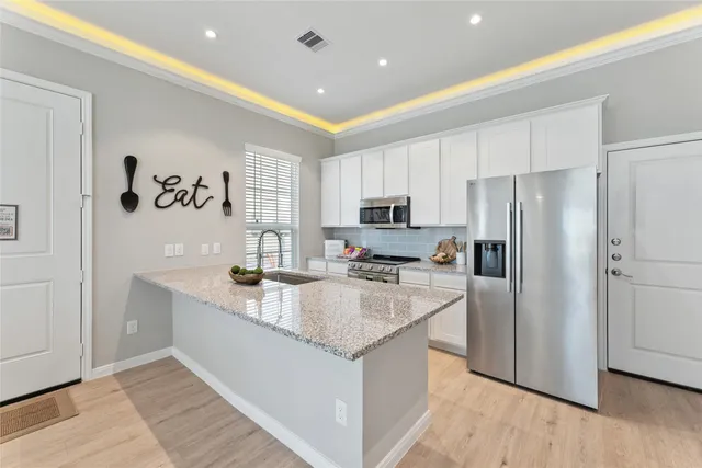 a large kitchen with stainless steel appliances granite countertop a refrigerator a sink dishwasher a stove and white countertops with wooden floor