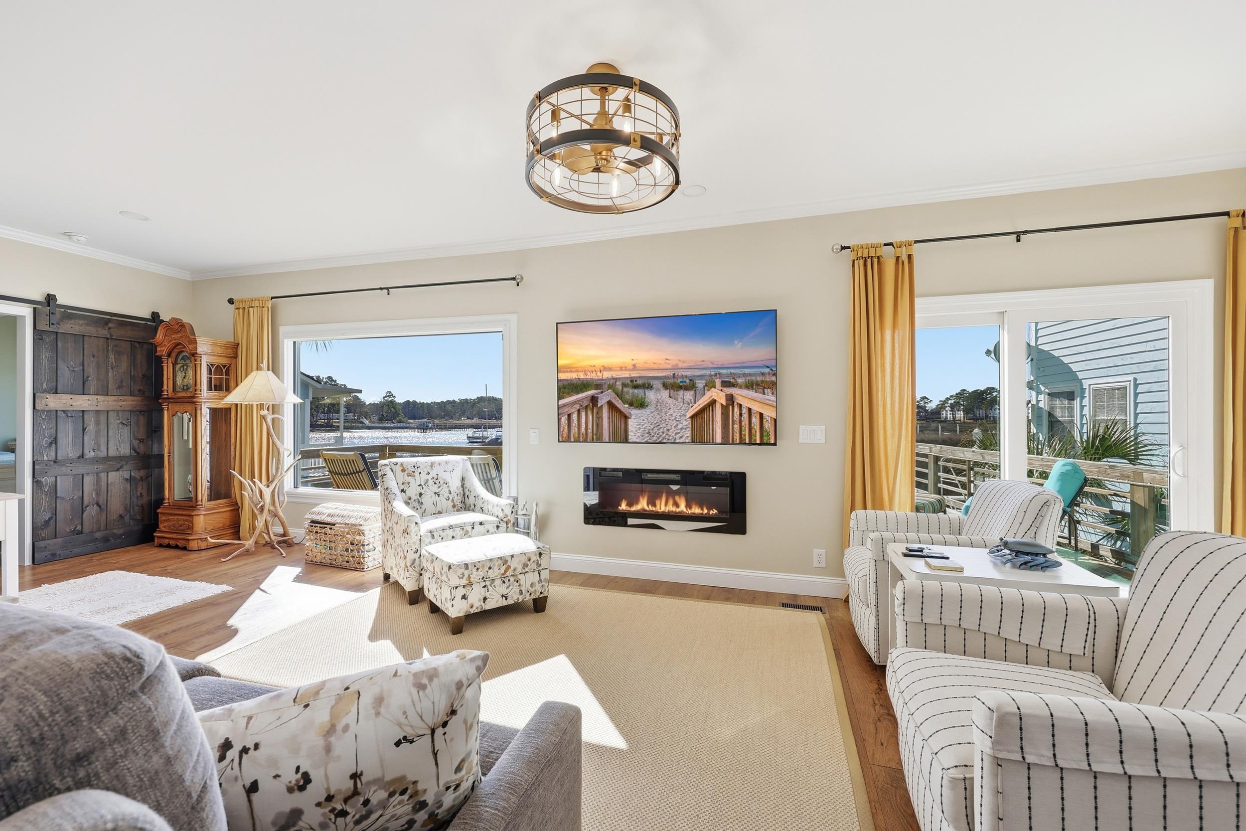 4524 Landing Road Little River, SC 29566 - Photo 12 of 40 Living room featuring a barn door, wood finished floors, a glass covered fireplace, and crown molding