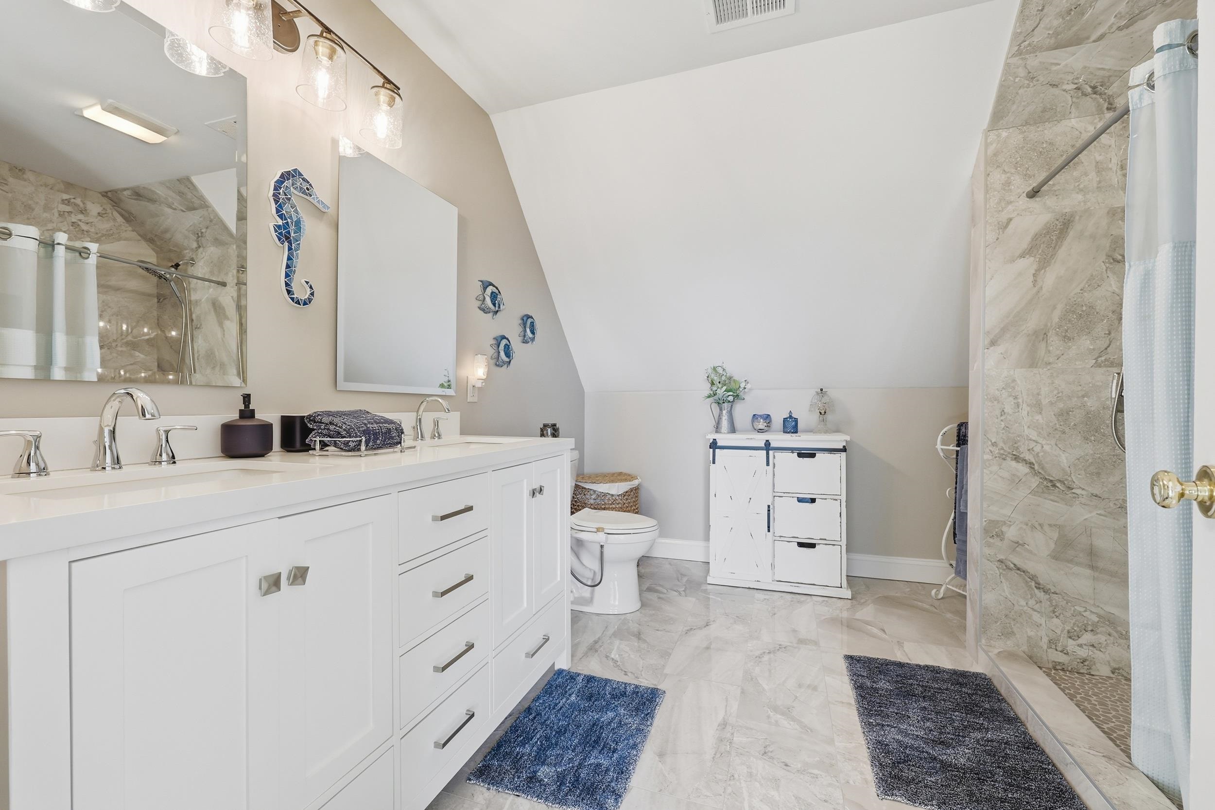 4524 Landing Road Little River, SC 29566 - Photo 22 of 40 Bathroom featuring a tile shower, light marble finish flooring, double vanity, and lofted ceiling