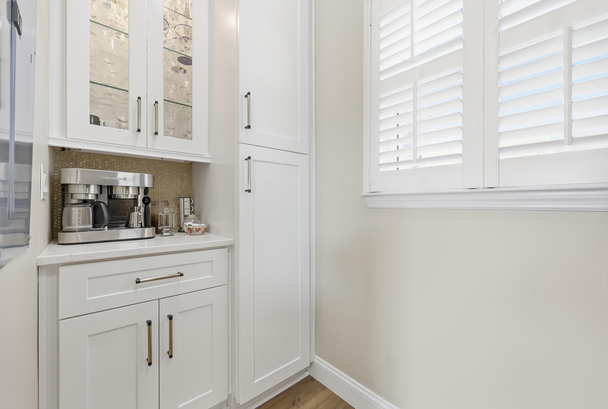 4524 Landing Road Little River, SC 29566 - Photo 9 of 40 Bar area featuring glass insert cabinets, white cabinets, tasteful backsplash, light stone countertops, and light wood-style floors