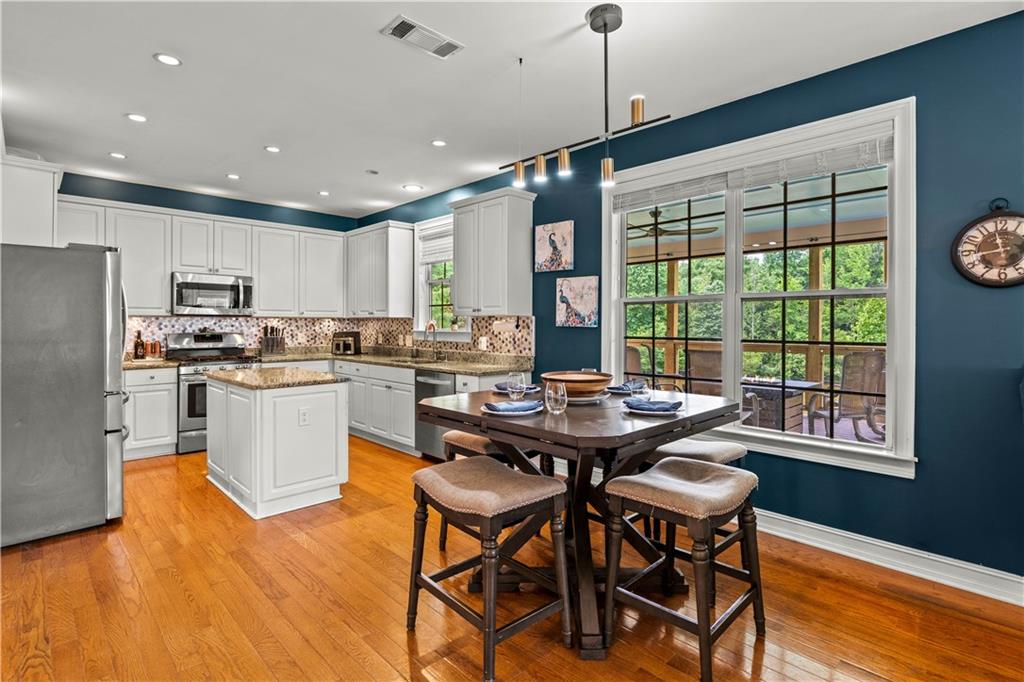 638 Glen Valley Way Dacula, GA 30019 - Photo 3 of 61 a open dining room with stainless steel appliances granite countertop a stove a refrigerator a kitchen island a dining table and chairs with wooden floor