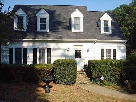a view of a brick house with plants in front of building