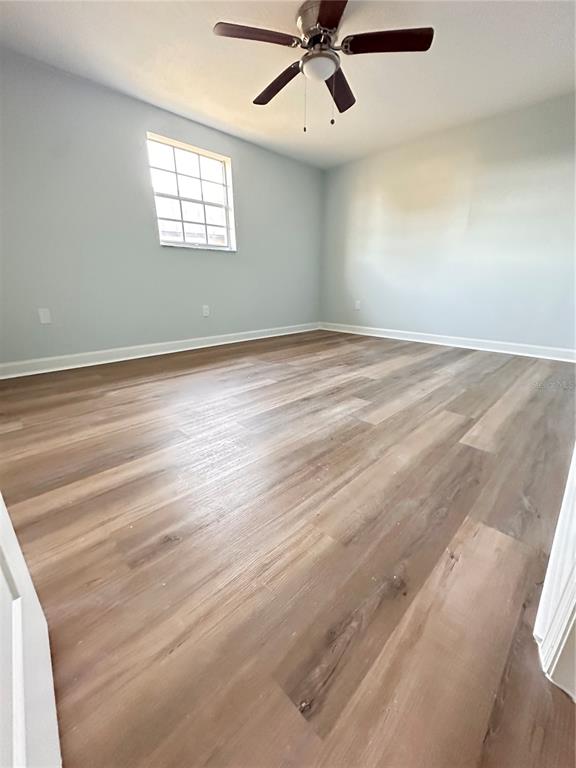 4407 Summersun Drive New Port Richey, FL 34652 - Photo 19 of 34 an empty room with wooden floor fan and windows