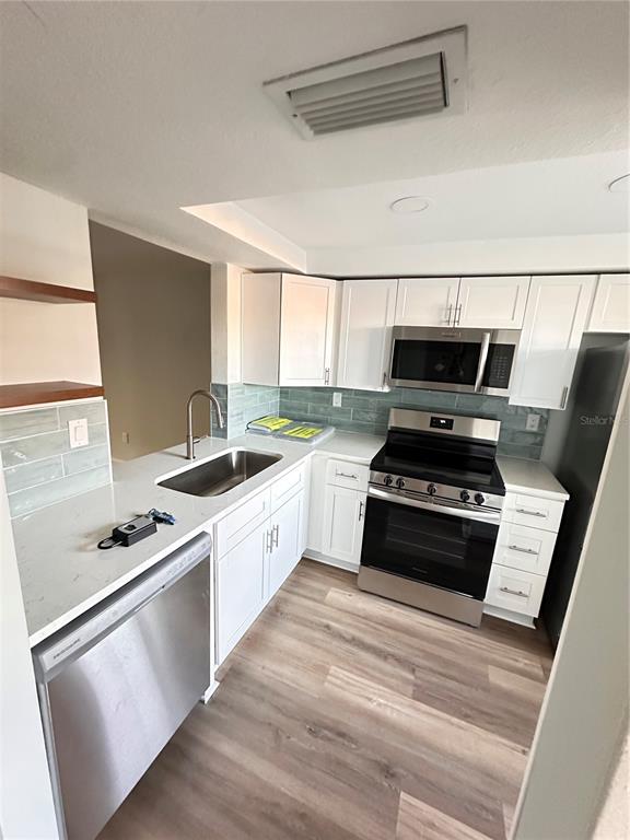 4407 Summersun Drive New Port Richey, FL 34652 - Photo 7 of 34 a kitchen with stainless steel appliances a stove a sink and white cabinets