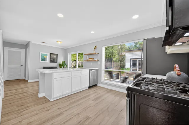 a kitchen with stainless steel appliances granite countertop a stove top oven a sink dishwasher and a refrigerator with wooden floor