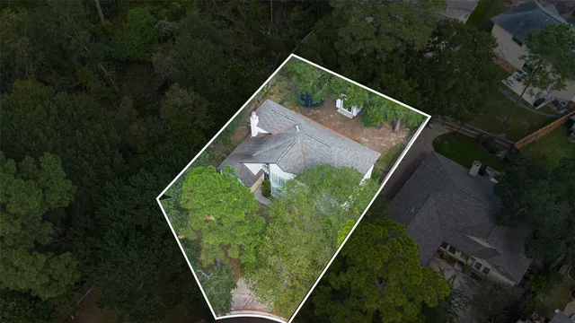 an aerial view of a house with a yard and trees all around