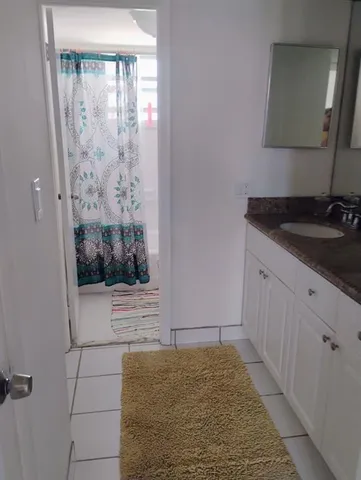 a bathroom with a granite countertop sink a mirror and shower
