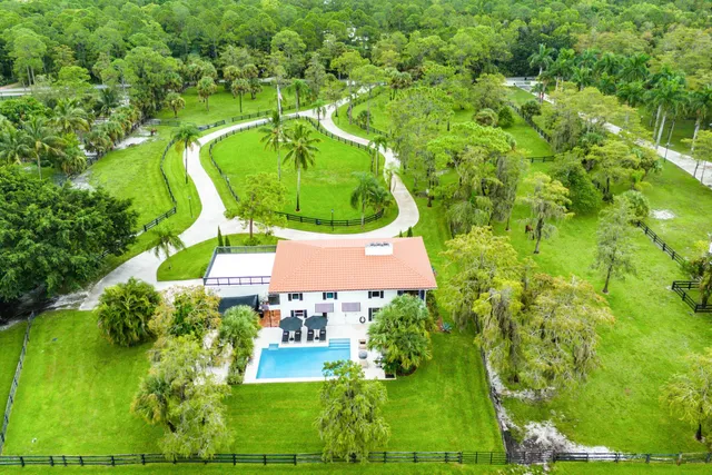 an aerial view of a house with a yard and trees all around