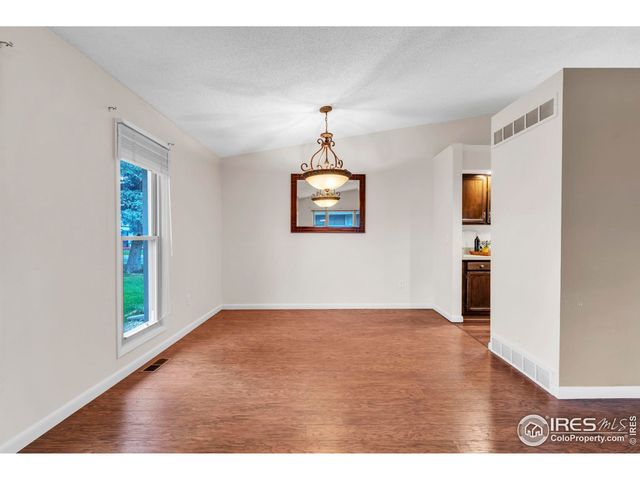 a view of an empty room with wooden floor and windows