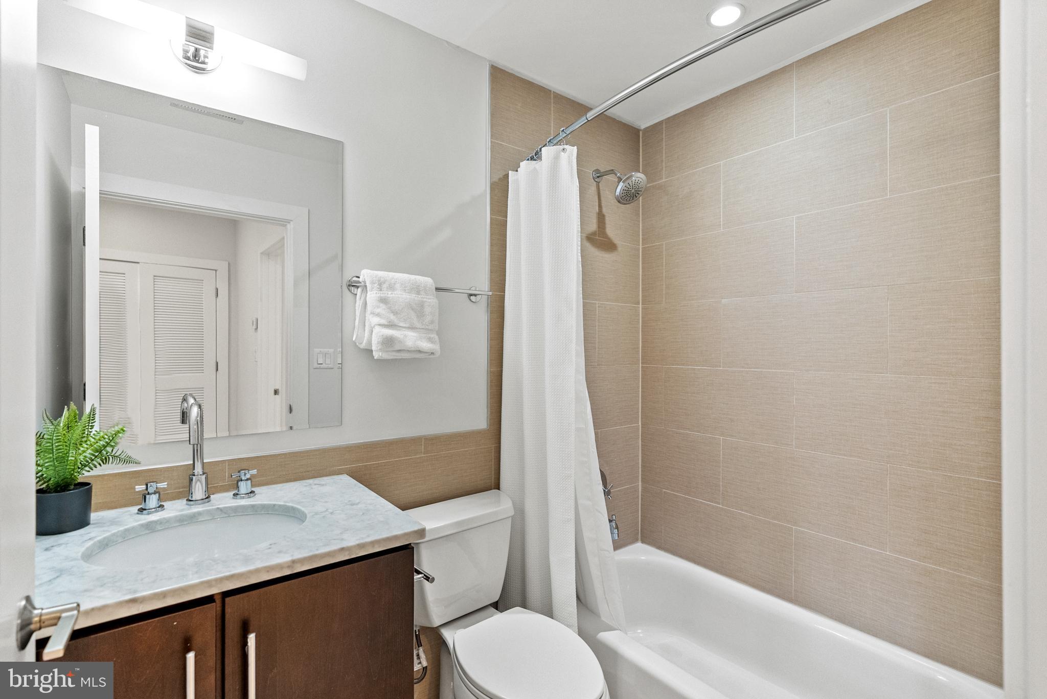 2101 11th Street Northwest, Unit 302 Washington, DC 20001 - Photo 16 of 26 a bathroom with a granite countertop sink toilet a large mirror a shower and a bathtub