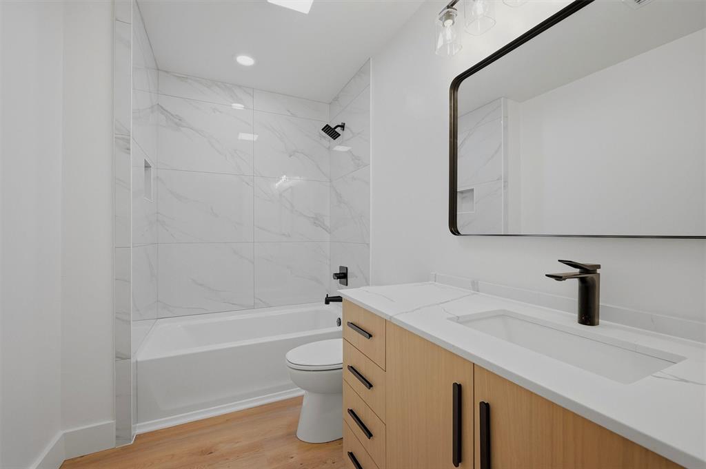 410 Arkansas Road Sadler, TX 76264 - Photo 22 of 40 Modern bathroom featuring a contemporary vanity with a rectangular undermount sink, matte black fixtures, and wood-finish flooring