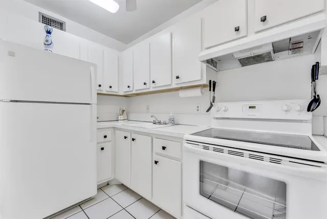 a kitchen with granite countertop white cabinets and white appliances
