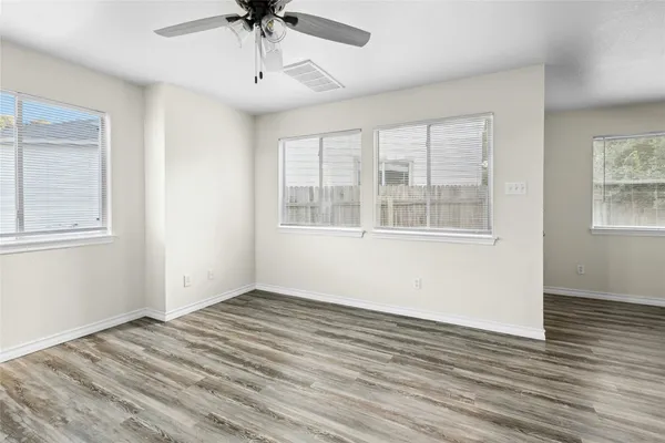 a view of empty room with wooden floor and fan