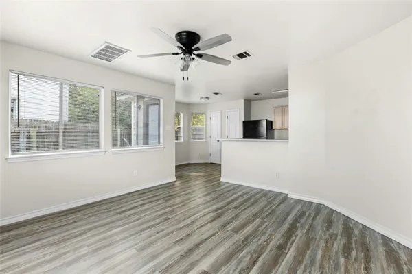 a view of an empty room with a window and wooden floor