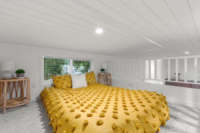 a large bed sitting in a bedroom next to a window with outer view