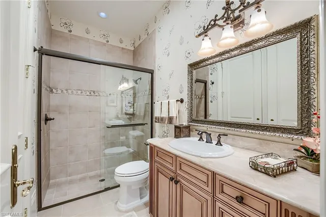 a bathroom with a granite countertop sink a toilet a mirror and shower